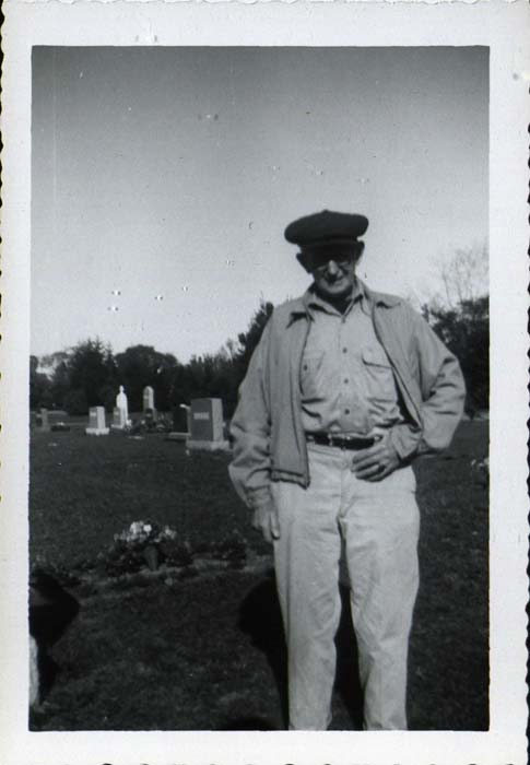 Photograph, man standing in cemetery